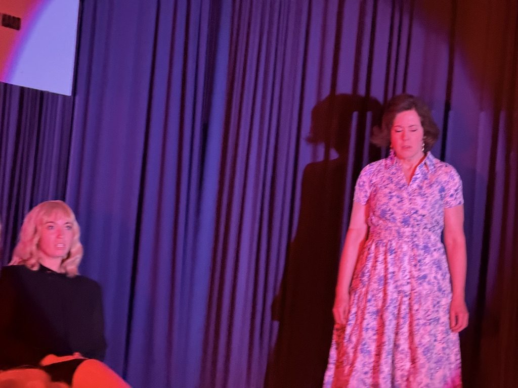 Narrator in red light, hat tilted